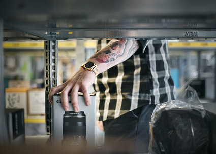 Tättowierter Arm hinter Regal Bras tatoué derrière une étagère